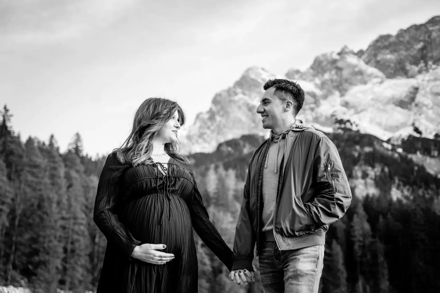 Paar blickt sich an und lächelt, Babybauchfotos am Eibsee, authentisch
