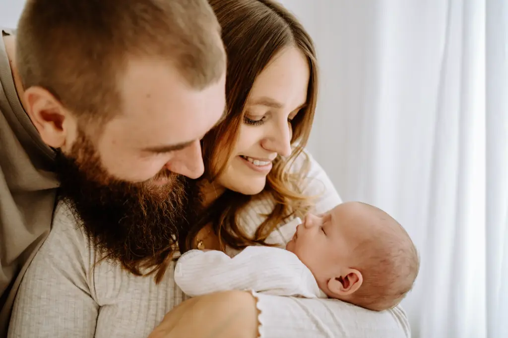 Baby liegt im Arm von Mama und Papa und genießt den ruhigen Moment