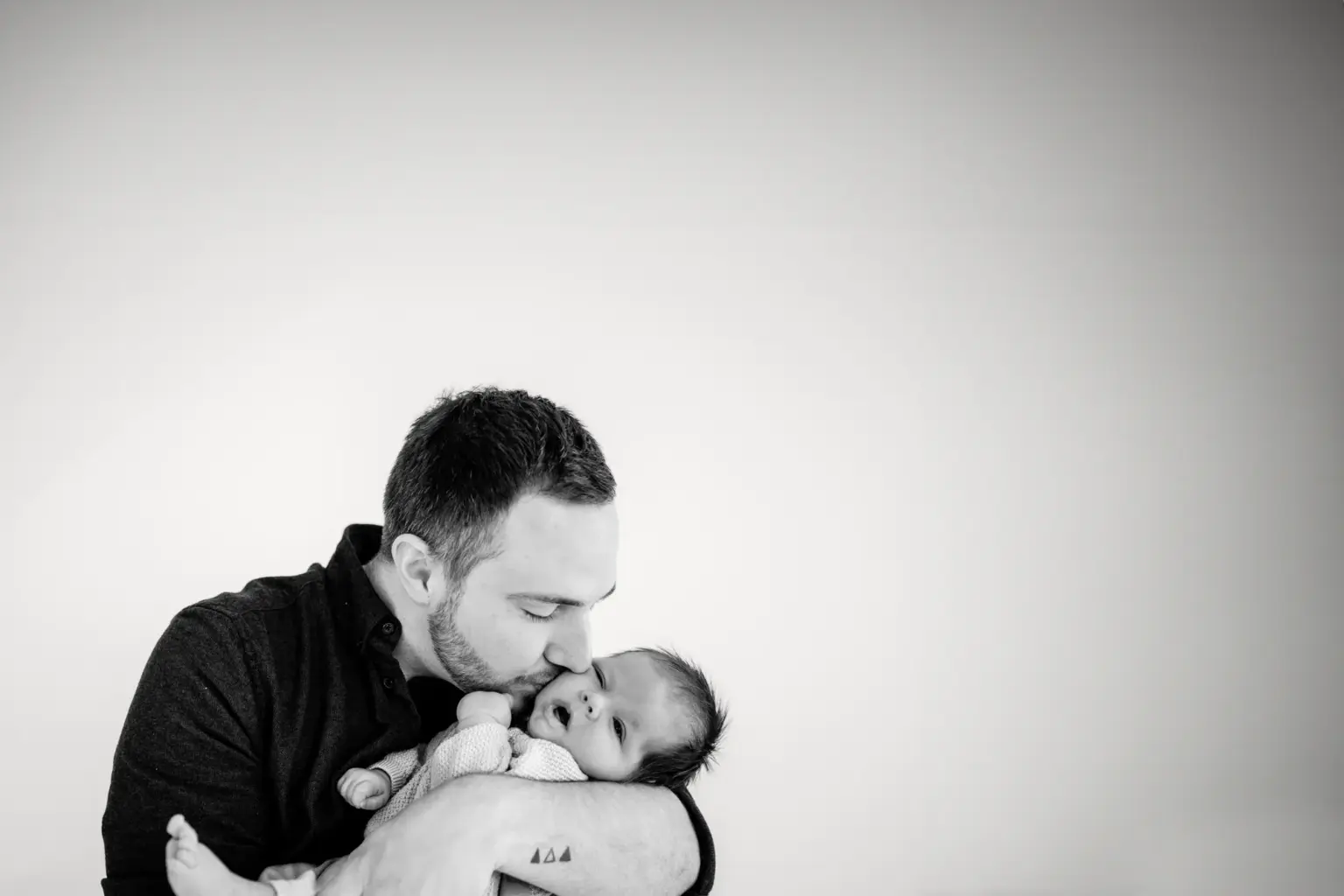 Papa hält Baby nah am Herzen, natürliche Babyfotos im Studio Weilheim