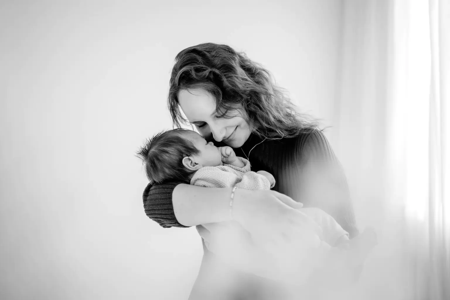 Mama kuschelt Neugeborenes, inniger Moment, cleanes Studiofoto