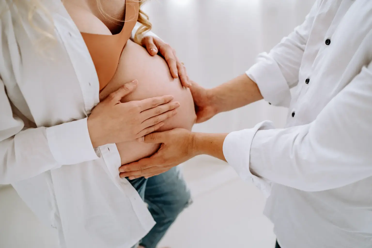 Mann hält beide Hände an den Babybauch
