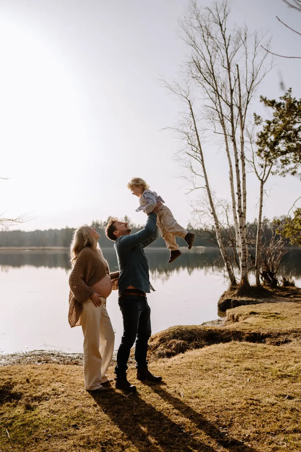 Familie hat Spaß beim Babybauchshooting am See in Weilheim