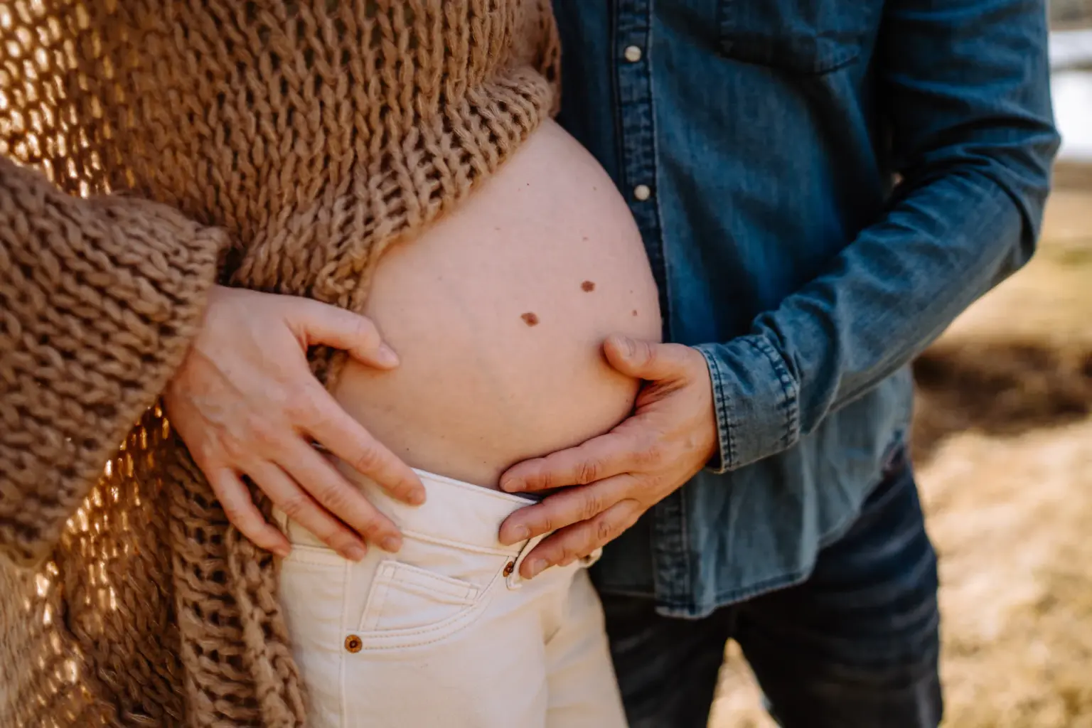 Papa hält den Bauch der werdenden Mama beim Babybauchshooting in Weilheim